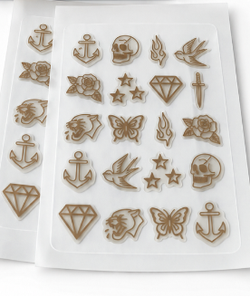 BlemInk tattoo breakouts kit showing a brown cardboard box and 2 sheets of clear plastic sheets containing various tattoo designs like anchors, skulls, diamonds, and butterflies.